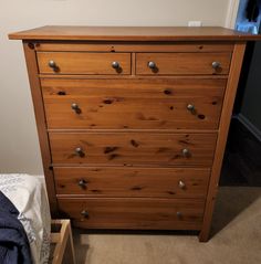 a wooden dresser sitting next to a bed in a room with carpeted flooring