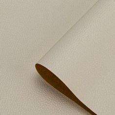 a close up view of a white leather textured material with a brown line at the end