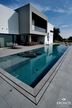 an empty swimming pool in front of a modern house