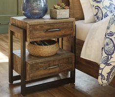 a nightstand with a basket on it next to a bed