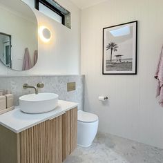 a bathroom with a sink, toilet and mirror on the wall next to a towel rack