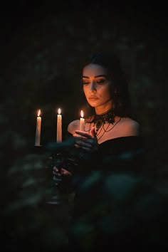 a woman holding three candles in her hands