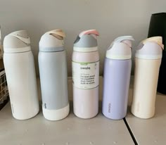 four different types of thermos are lined up in a row on a counter