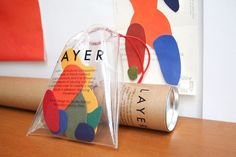 a paper tube with some colorful stickers on it next to a bag that says ayer