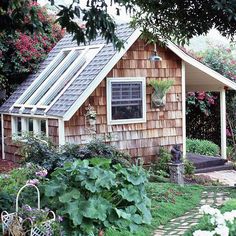 a small wooden house surrounded by flowers and trees