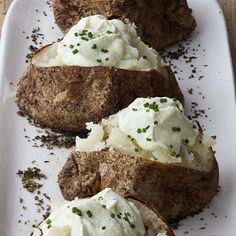 three pieces of meat and mashed potatoes on a white plate with green sprinkles