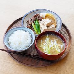 a plate with rice, meat and vegetables on it next to chopsticks in bowls