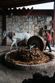 a white horse standing next to a pile of wood on top of a stone floor