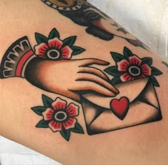 a close up of a person's arm with an envelope and flowers on it