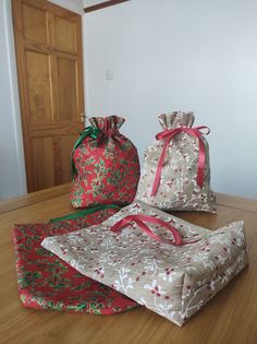 three bags sitting on top of a wooden table next to each other with red bows