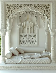 a white bed sitting under a window next to a wooden structure with carvings on it