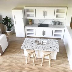 a model kitchen with white cabinets and marble counter tops, two stools at the center