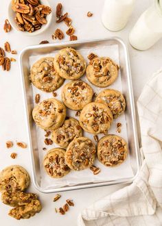 pecan cookies on a baking sheet with chopped pecans next to it and a bowl of nuts