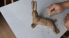 a person is carving a wooden rabbit on a piece of paper