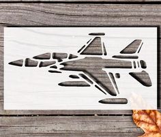 an airplane cutout is shown on a piece of wood next to a maple leaf