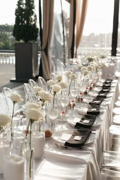 a long table is set with wine glasses and white flowers in vases on it