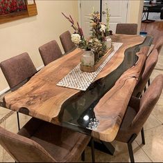 a dining room table made out of wood and metal legs with flowers in vase on top