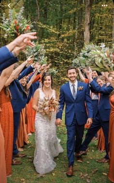 a bride and groom walking through the woods with their wedding party throwing confetti in the air