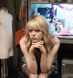 a woman sitting on top of a chair next to a mannequin