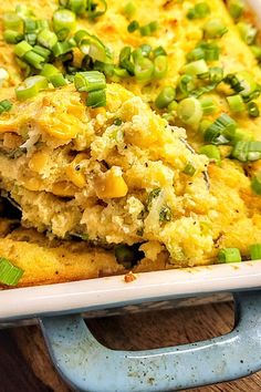 a casserole dish with green onions and other toppings in it on a wooden table