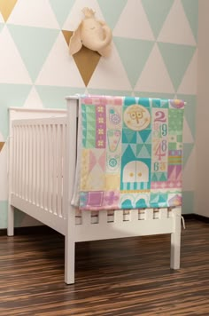 a baby crib with a blanket on top of it in front of a wall