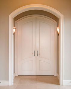 an empty hallway with two doors leading to another room in the same area and light fixtures on either side