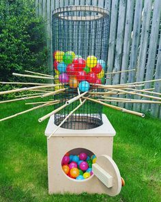 a cage filled with lots of colorful balls and wooden sticks sticking out of the top