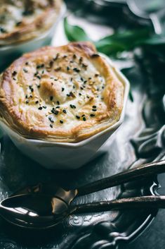 two small pies sitting on top of a metal tray next to spoons and utensils