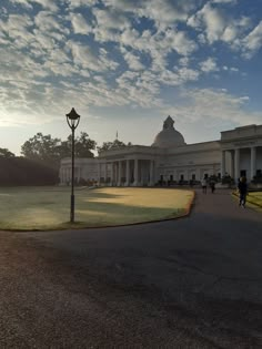 people walking in front of a large white building with columns and pillars on the side