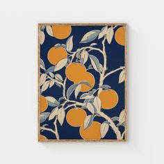 an orange tree with leaves on a blue background is framed in wood and hangs on the wall