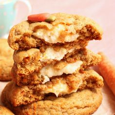 three cookies stacked on top of each other with cream cheese and carrots in the background