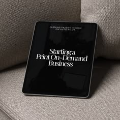 a black book sitting on top of a couch next to a gray chair and pillow