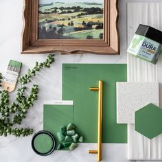 some green paint and other items on a white table with a painting in the background