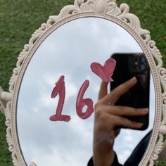 a person taking a selfie in front of a mirror with the number 16 painted on it