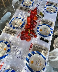 the table is set with plates, silverware and tomatoes