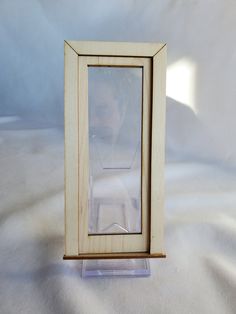 a small wooden frame with a clear glass window on the front and bottom side, sitting on a white surface