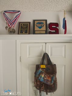 there is a purse hanging on the wall next to two awards and plaques above it