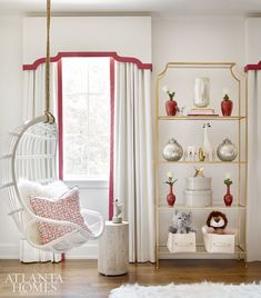 a living room with white furniture and red trim on the windowsill, along with a hanging chair