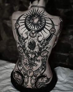 the back of a woman's body with tattoos on it