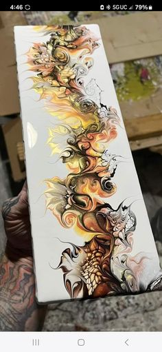 a person holding up a painting on top of a white board with flames and dragon designs