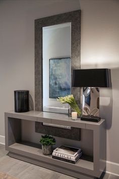 a table with a mirror, lamp and vase on it