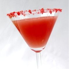 a red drink in a martini glass with sprinkles on the rim and garnish