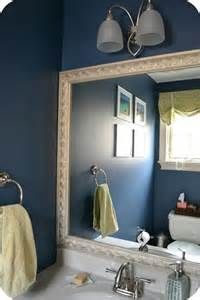 a bathroom with blue walls and a white sink under a large mirror above the toilet