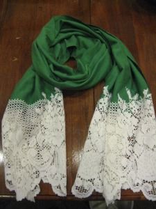 a green scarf with white lace on it