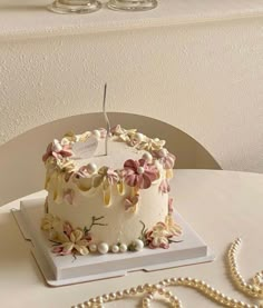 a white cake sitting on top of a table next to pearls and a bead necklace