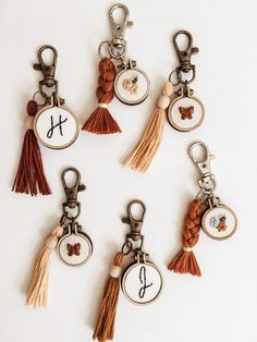 six different key chains with tassels and charms attached to each other on a white surface