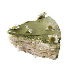 a piece of cake with green frosting and daisies on the top, cut in half