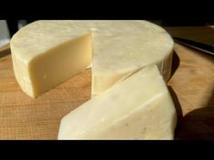 a piece of cheese sitting on top of a wooden cutting board