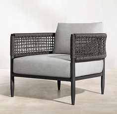 a gray and black chair sitting on top of a cement floor next to a white wall