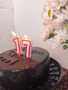 a chocolate cake with two lit candles on it